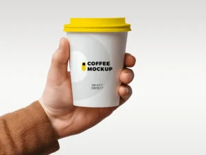 Coffee cup mockup held in hand with blank label area for branding.